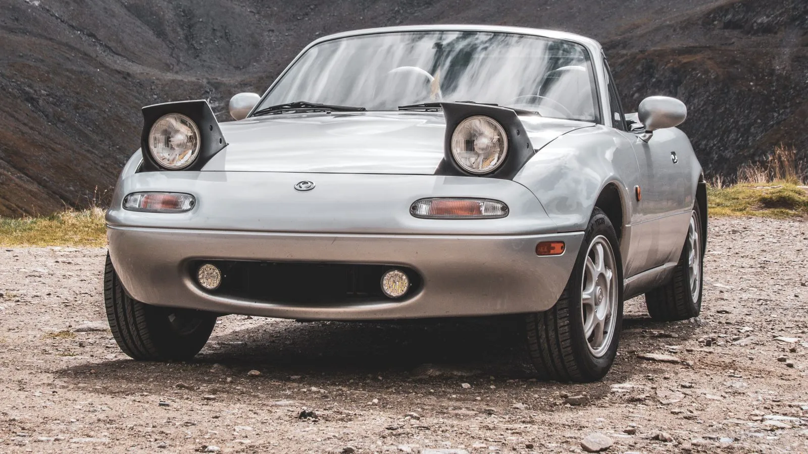 Mazda MX-5 NA rojo con faros escamoteables y capota bajada